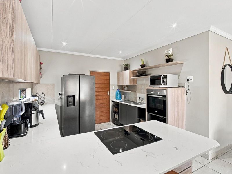 Modern kitchen featuring sleek cabinetry, stone countertops, integrated electric hob, built-in oven, and high-quality finishes throughout.