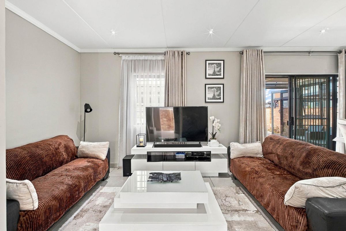 A well-maintained living room featuring tiled flooring, recessed downlighting, and a sliding glass door providing access to the outdoor area.