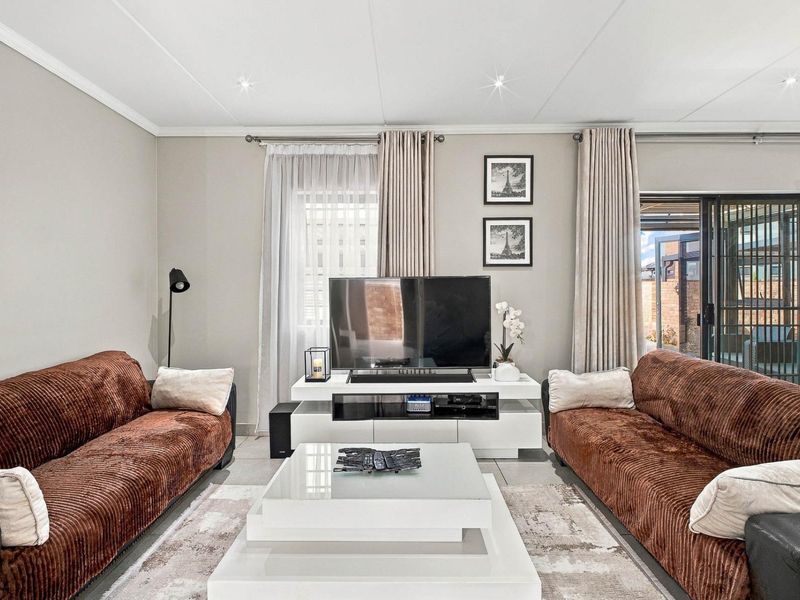 A well-maintained living room featuring tiled flooring, recessed downlighting, and a sliding glass door providing access to the outdoor area.