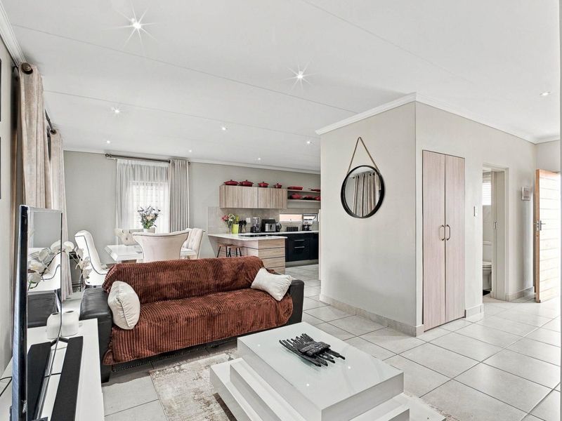 Spacious open-plan living and dining area featuring tiled floors, recessed lighting, and a modern kitchen with built-in cabinetry and a central island.