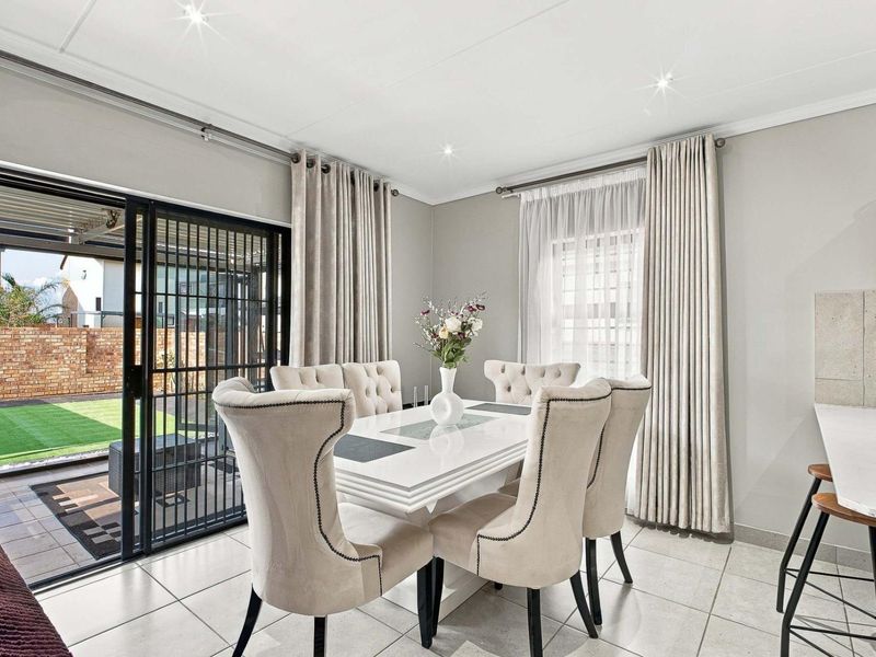 Bright open-plan dining area featuring tiled floors, recessed lighting, and a sliding glass door providing direct access to the rear patio and garden.