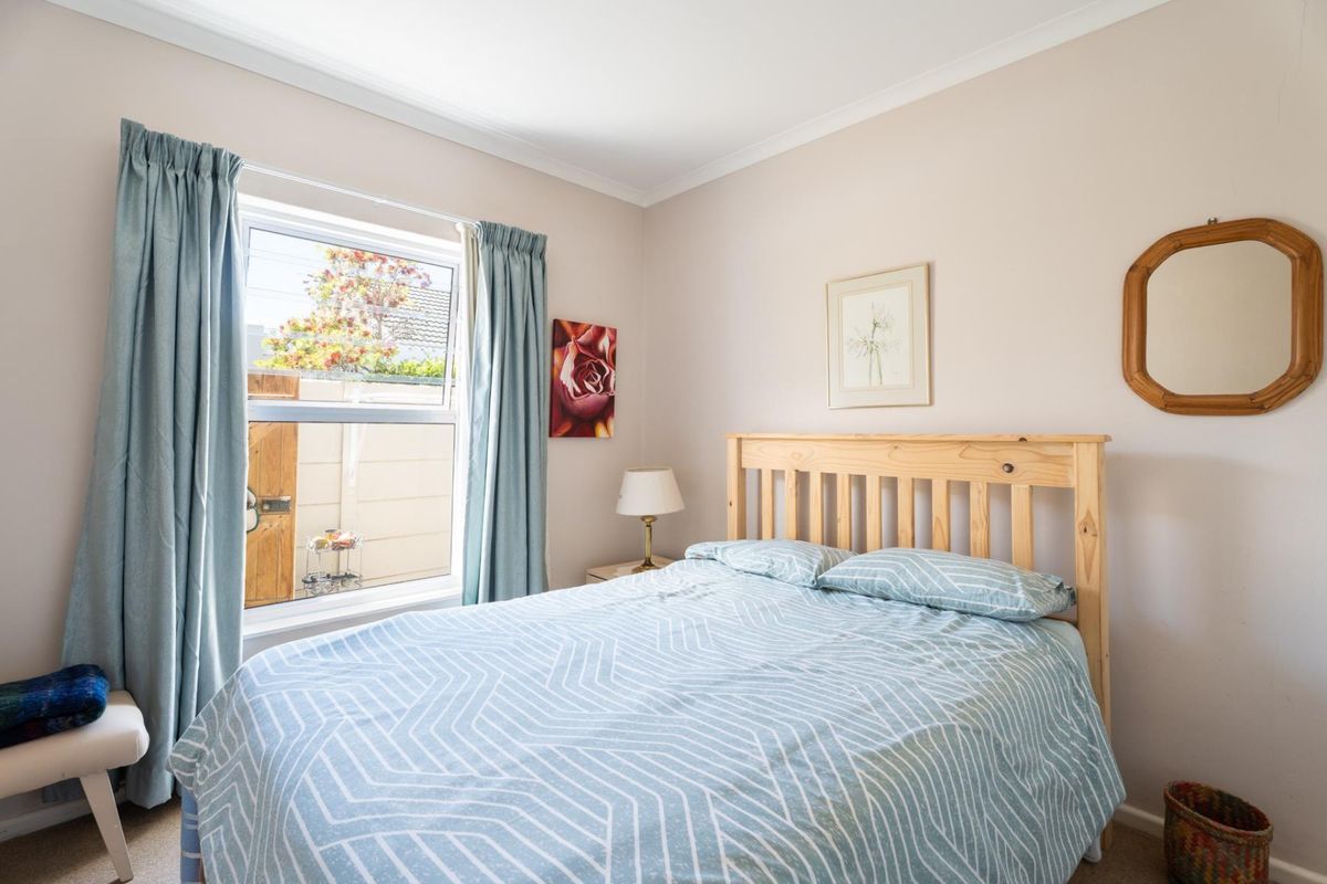 A well-lit bedroom featuring neutral wall tones, coving, and a window overlooking the exterior area.
