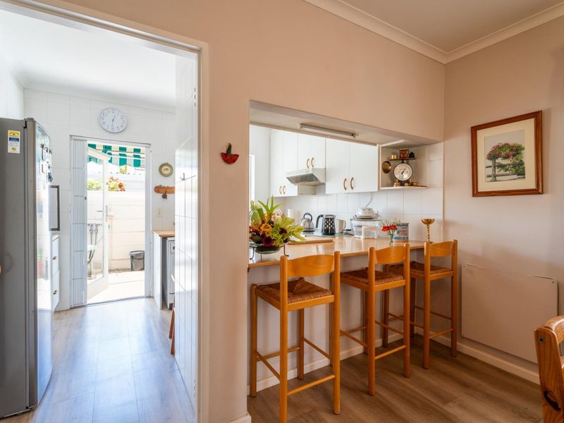 Open plan kitchen area featuring a breakfast bar, built-in cabinetry, and a tiled splashback, with direct access to an outdoor area.
