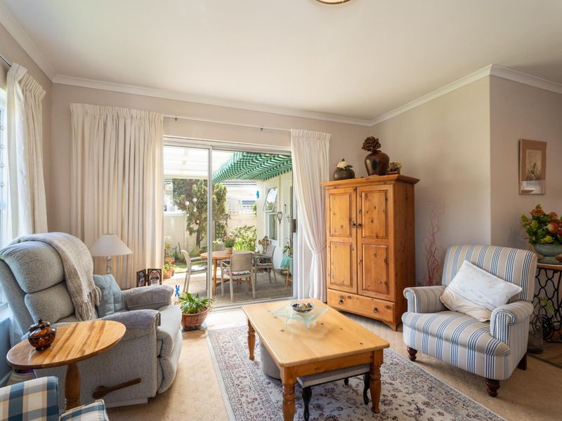 A comfortable living room featuring a sliding glass door that opens onto a covered patio area, providing natural light and garden access.