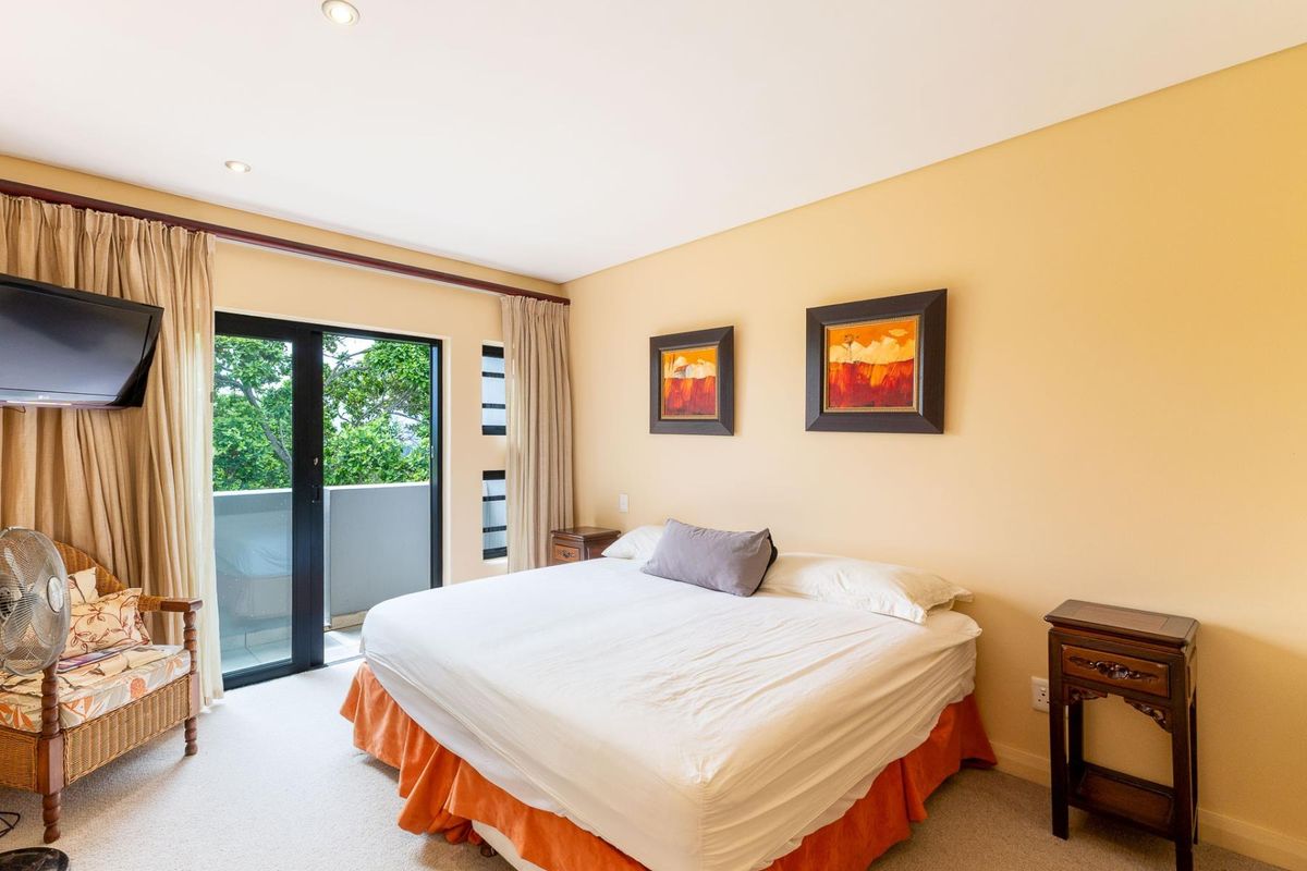 A well-lit bedroom featuring neutral walls, carpeted flooring, and a sliding glass door providing access to an outdoor balcony area.