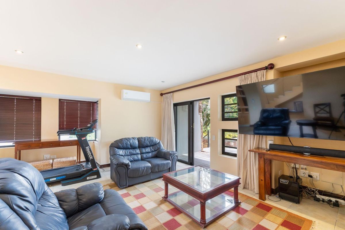 A comfortable living room featuring tiled flooring, recessed lighting, a wall-mounted air conditioner, and sliding glass doors providing access to the outdoor area.