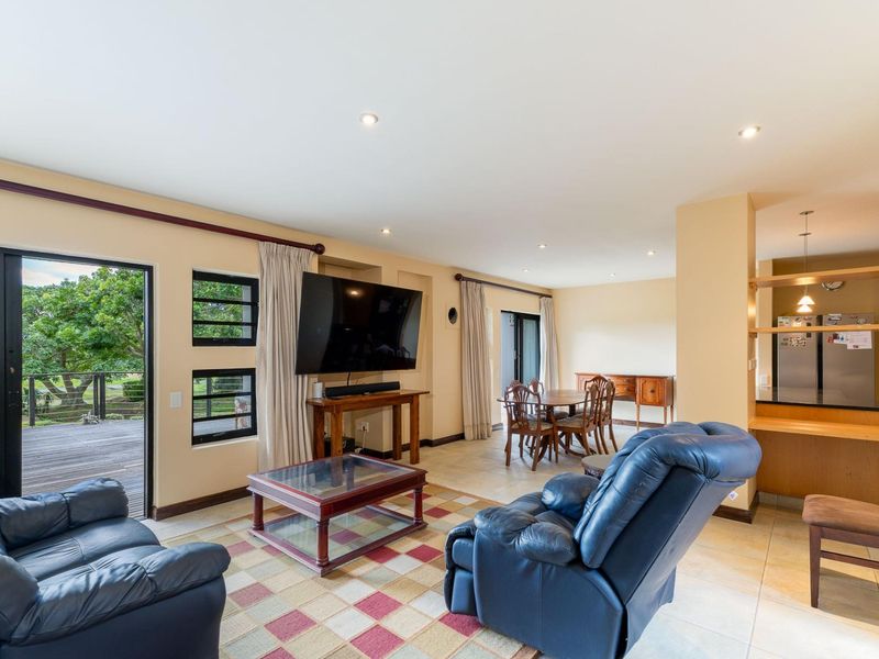 Spacious open-plan living and dining area featuring tiled floors, recessed lighting, and direct access to an outdoor deck through sliding glass doors.
