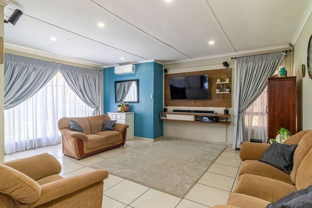 A spacious living room featuring tiled flooring, a built-in media console, and a split-system air conditioner, offering a comfortable and functional family space.