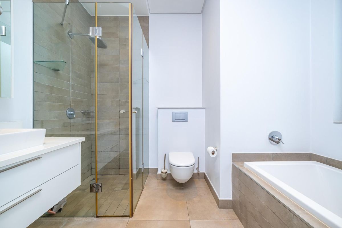 Modern bathroom featuring a glass-enclosed shower, wall-mounted toilet, built-in bathtub, and a sleek vanity with a vessel sink.