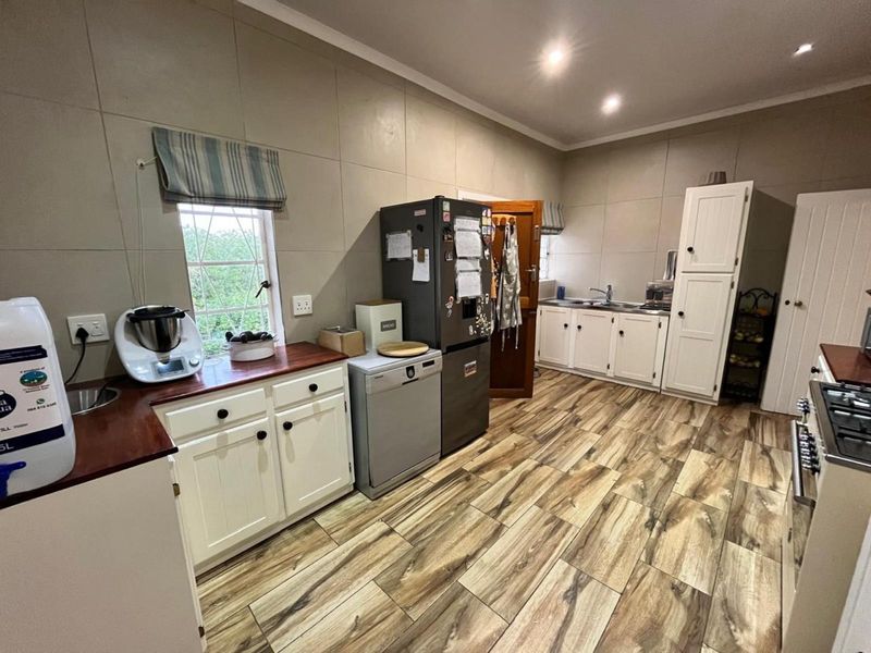 A functional kitchen featuring white cabinetry, wooden countertops, tiled walls, and wood-look floor tiles, offering a practical layout with ample storage space.