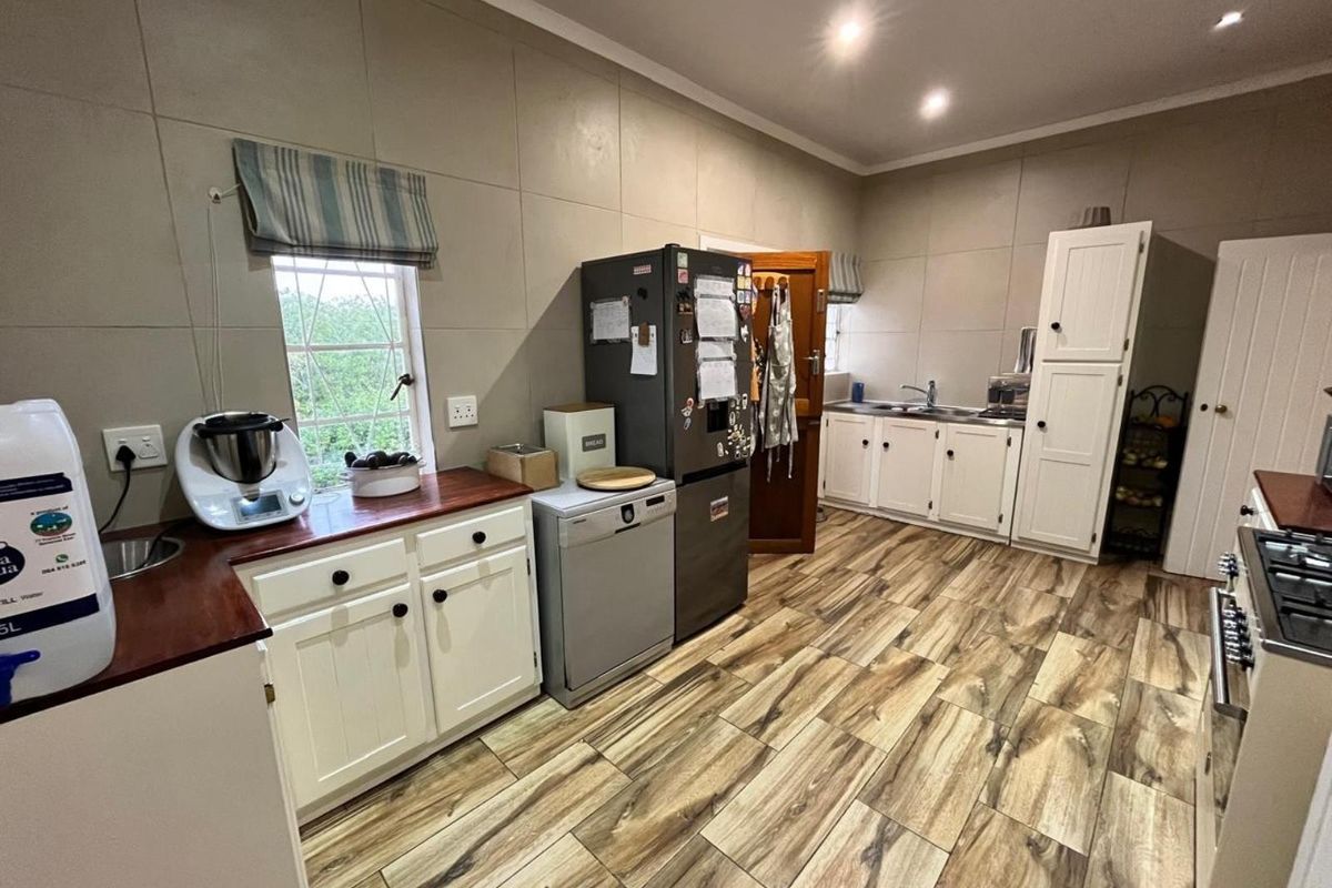 A functional kitchen featuring white cabinetry, wooden countertops, tiled walls, and wood-look floor tiles, offering a practical layout with ample storage space.