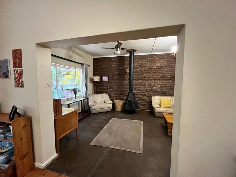 A cozy living room featuring an exposed brick wall, a prominent freestanding fireplace, and a ceiling fan, offering a warm and inviting atmosphere.