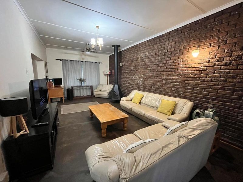Spacious living room featuring a prominent exposed brick wall, a freestanding fireplace, and a ceiling fan, offering a cozy and rustic atmosphere.