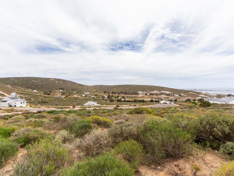 A scenic elevated view of the surrounding coastal landscape and residential development, showcasing the natural terrain and open space of the vacant land.
