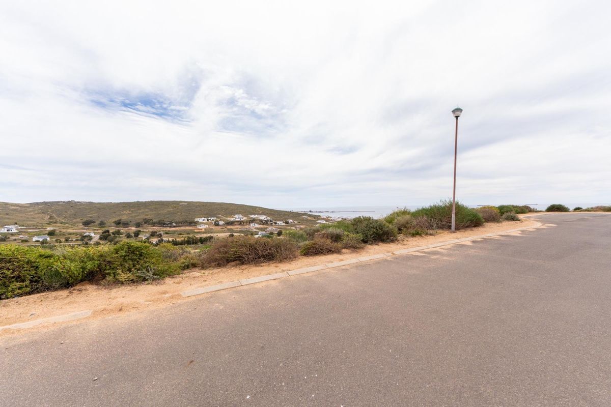 A scenic view overlooking the coastal landscape and surrounding residential area from the edge of a paved street.