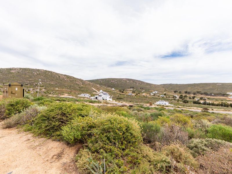 A scenic view of the surrounding natural landscape and distant residential properties, showcasing the open terrain and local vegetation.
