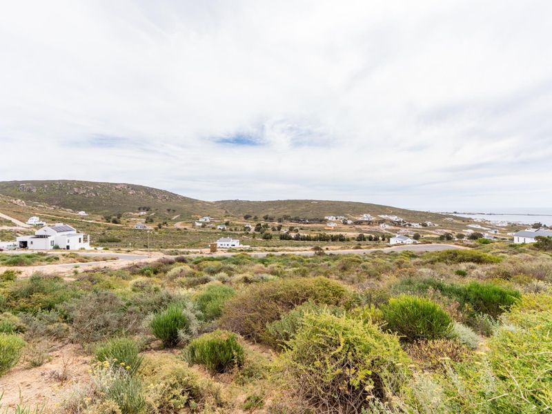 A scenic elevated view overlooking the surrounding coastal landscape, natural vegetation, and distant residential properties.