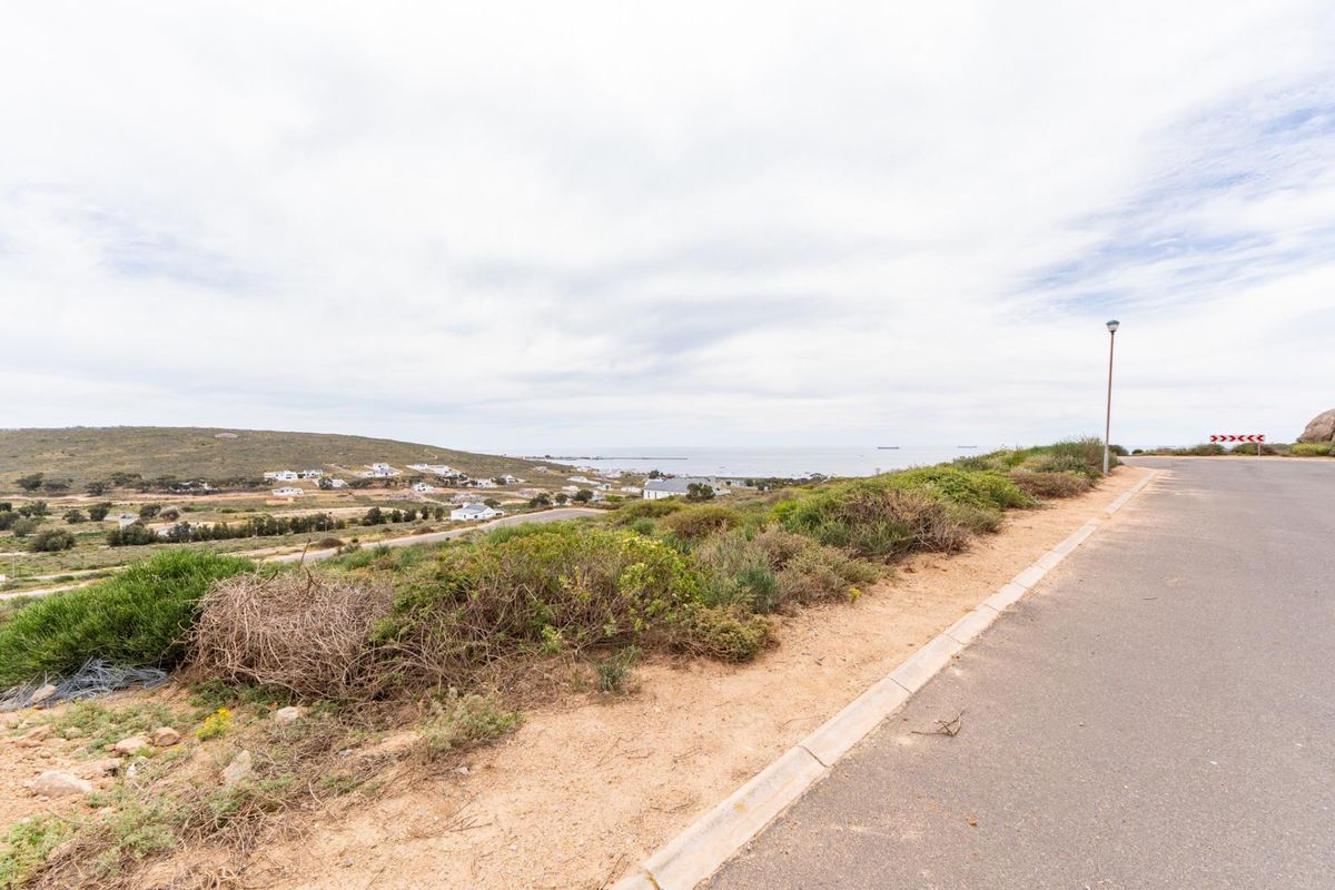 A scenic view overlooking the coastal landscape and surrounding residential area from the edge of a paved road.