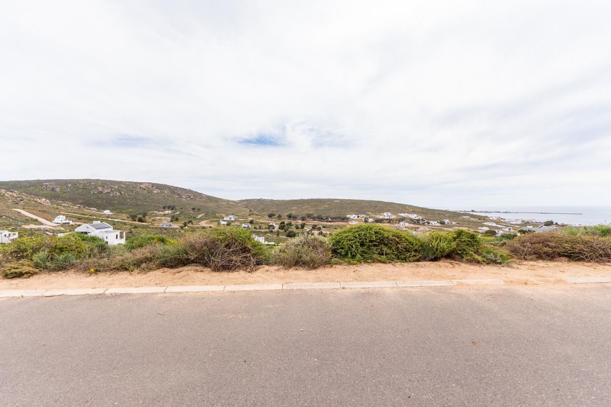 A wide-angle view of the surrounding landscape and coastal hillside from the paved road, showcasing the elevated position of the vacant land.