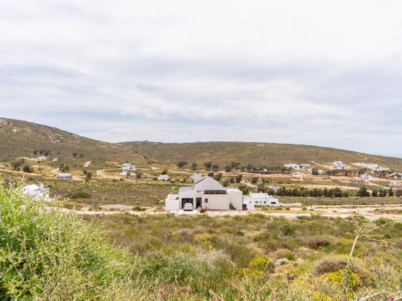 An elevated view of a modern residential property set within a natural, hilly landscape, showcasing the home's exterior architecture and surrounding environment.