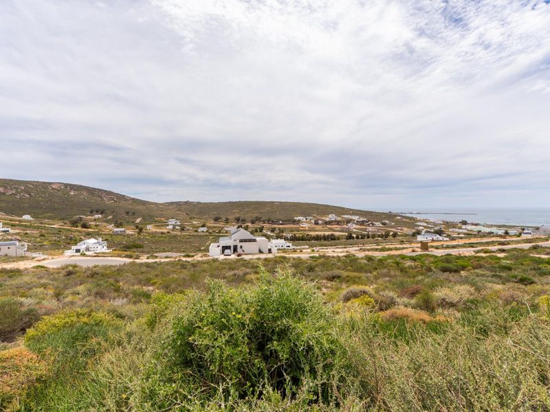 An elevated view of a coastal residential area featuring natural vegetation and surrounding landscape.