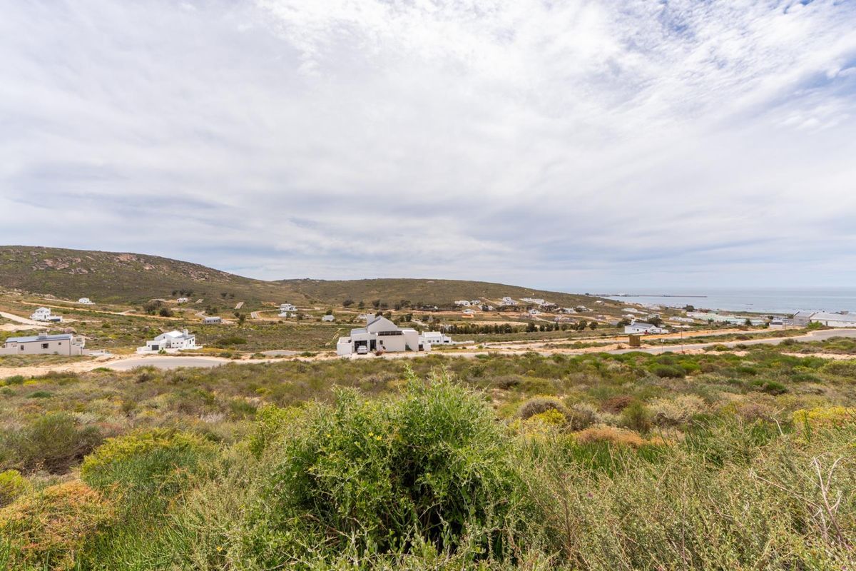 An elevated view of a coastal residential area featuring natural vegetation and surrounding landscape.