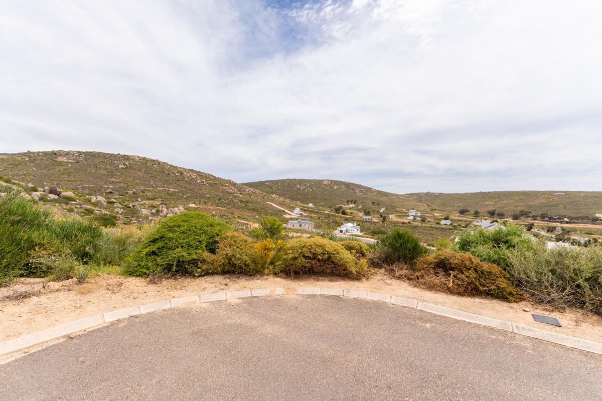 A scenic view overlooking the surrounding hilly landscape and residential area from a paved road.