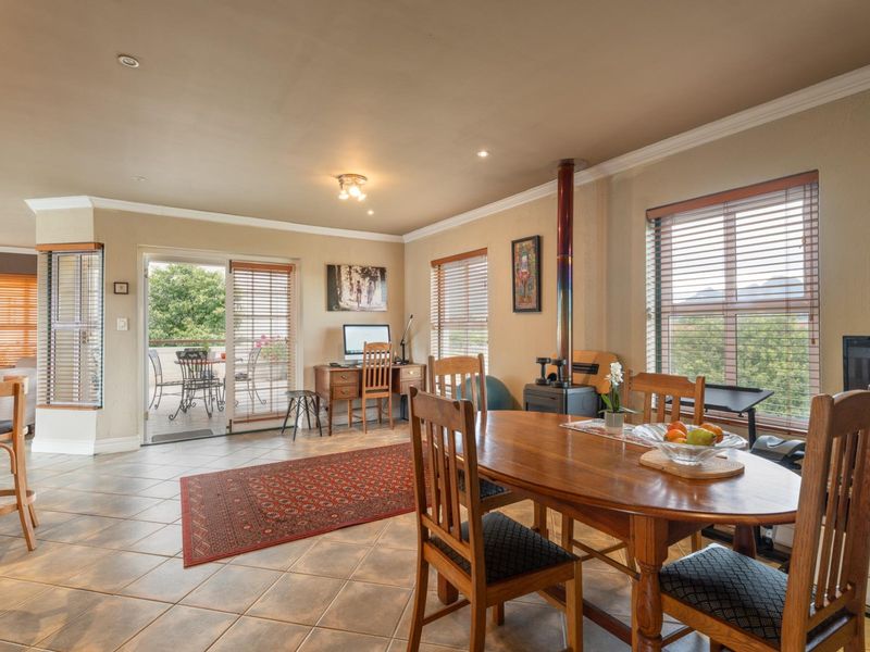Spacious open-plan living and dining area featuring tiled floors, a wood-burning fireplace, and direct access to an outdoor balcony through sliding glass doors.