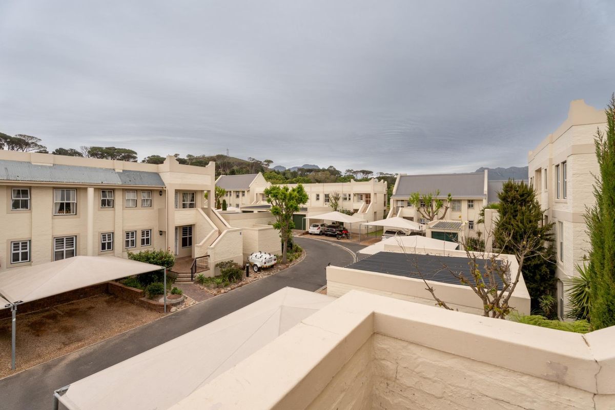 An elevated view of a residential apartment complex featuring paved driveways, covered parking bays, and multi-story buildings with neutral-toned masonry facades.