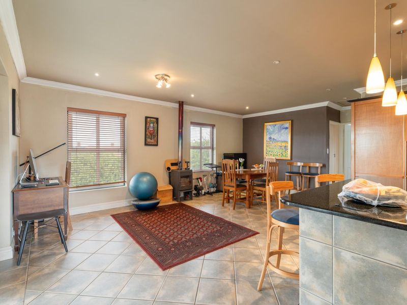 Spacious open-plan living and kitchen area featuring tiled flooring, a wood-burning stove, granite countertops, and modern lighting fixtures.