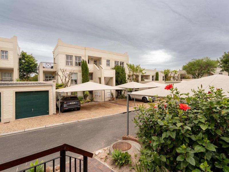 Exterior view of an apartment complex featuring covered parking bays, a garage, and well-maintained building facades.