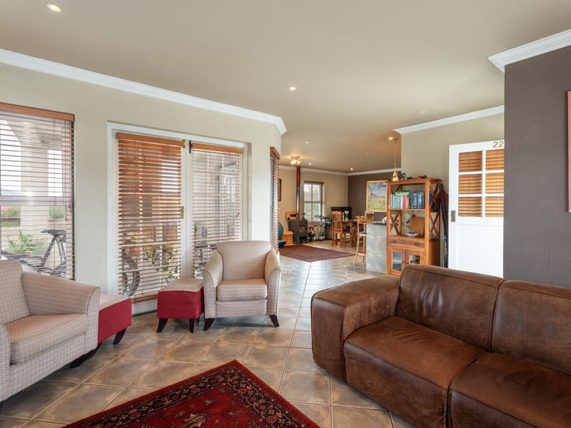 Spacious open-plan living area featuring tiled flooring, recessed lighting, crown molding, and a wood-burning stove, with direct access to an outdoor patio.