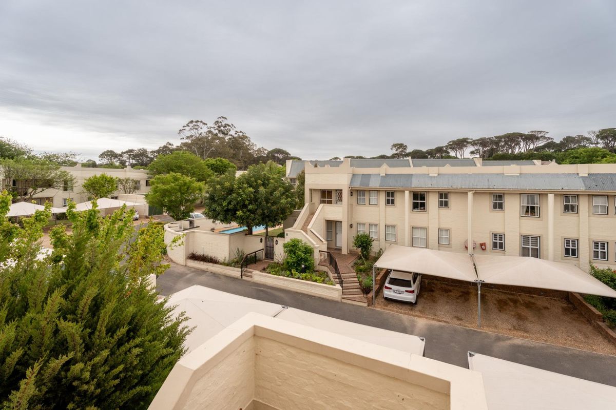 Elevated view of the apartment complex exterior, featuring brick facades, paved driveways, and covered parking bays within a landscaped residential estate.