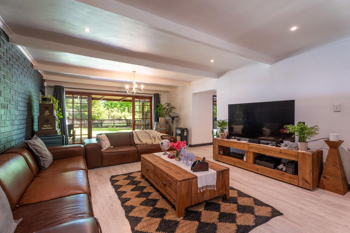 Spacious living room featuring a painted brick accent wall, exposed beam ceiling, and large timber sliding doors opening to the garden.