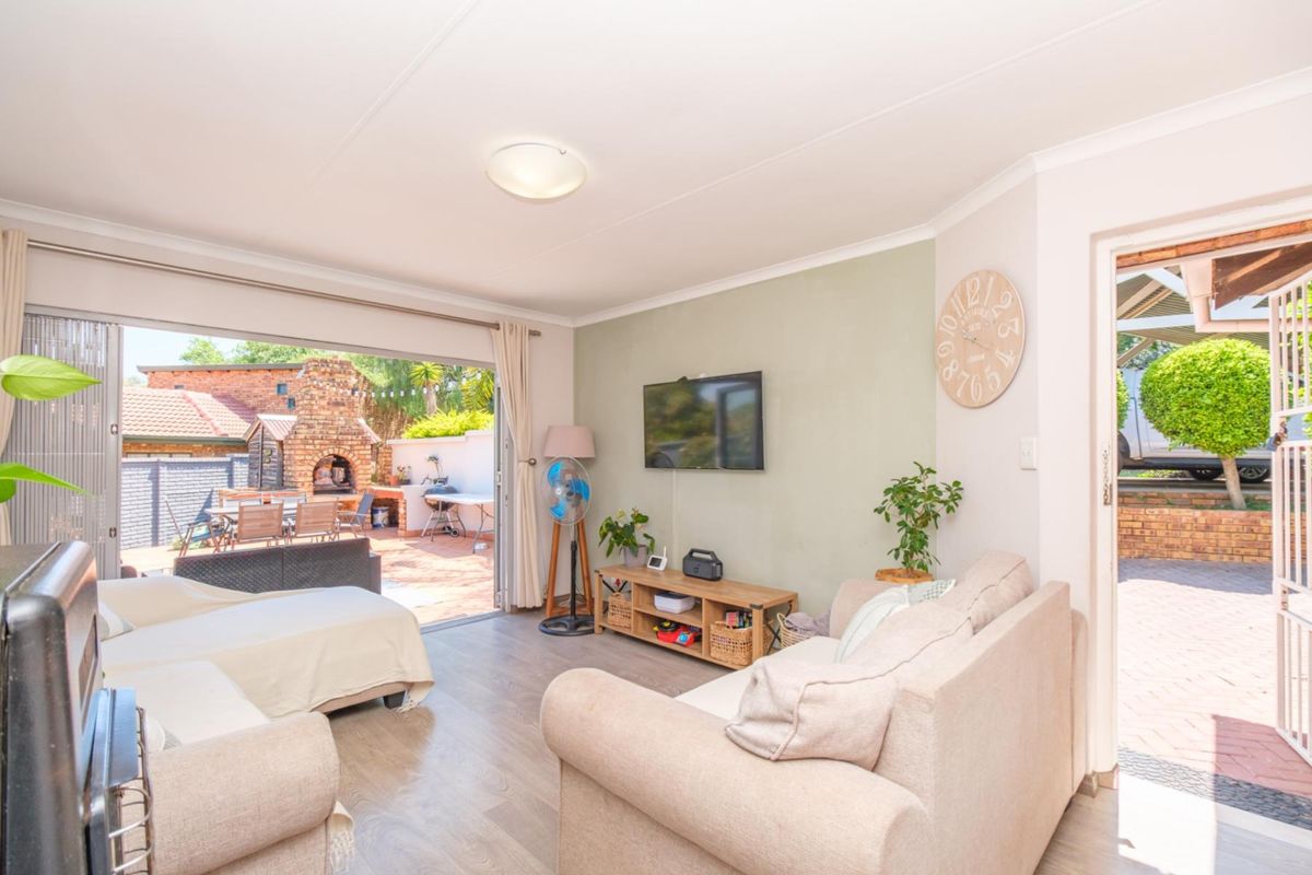 Bright living room featuring laminate flooring and large sliding glass doors that provide seamless access to the outdoor patio area.