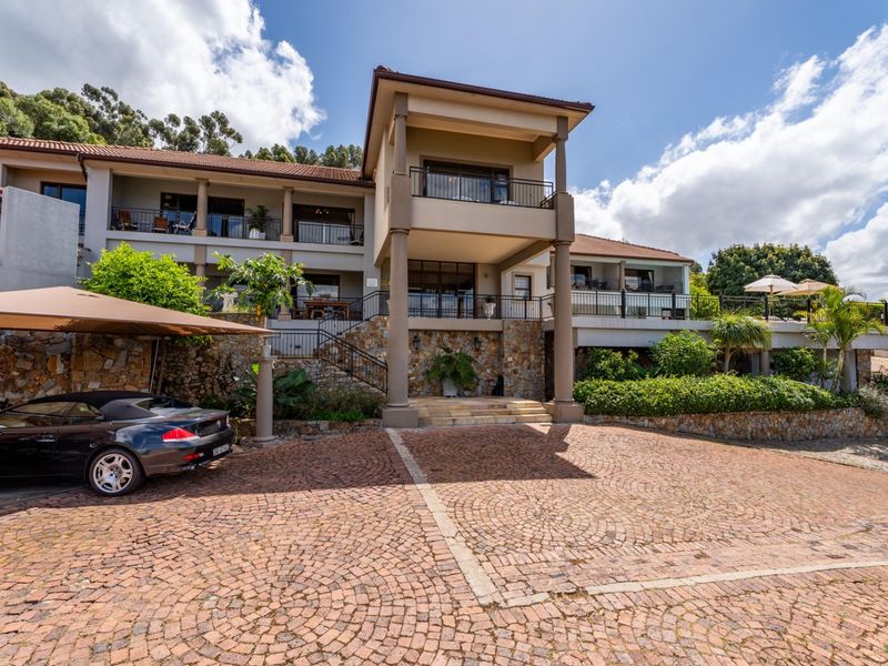 Impressive multi-level residence featuring a cobblestone driveway, stone-clad facade, and expansive balconies, showcasing a well-maintained architectural design.