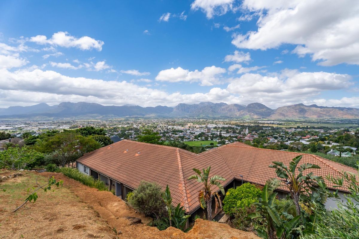An elevated aerial view of the property featuring a tiled roof, overlooking a sprawling town landscape with mountain vistas in the background.