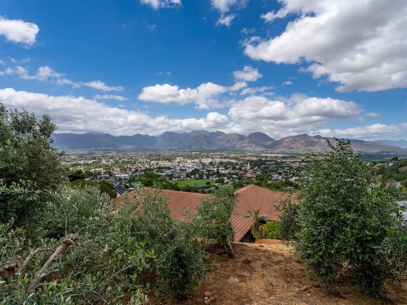 Elevated panoramic view overlooking the town and surrounding mountain range, featuring a clear perspective of the property's roofline and landscape.