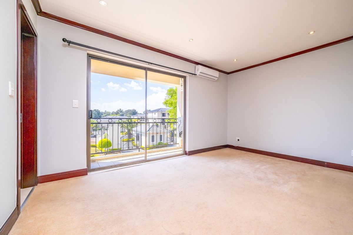 An empty bedroom featuring carpeted flooring, recessed lighting, an air conditioning unit, and a sliding glass door leading to a balcony with iron railings.