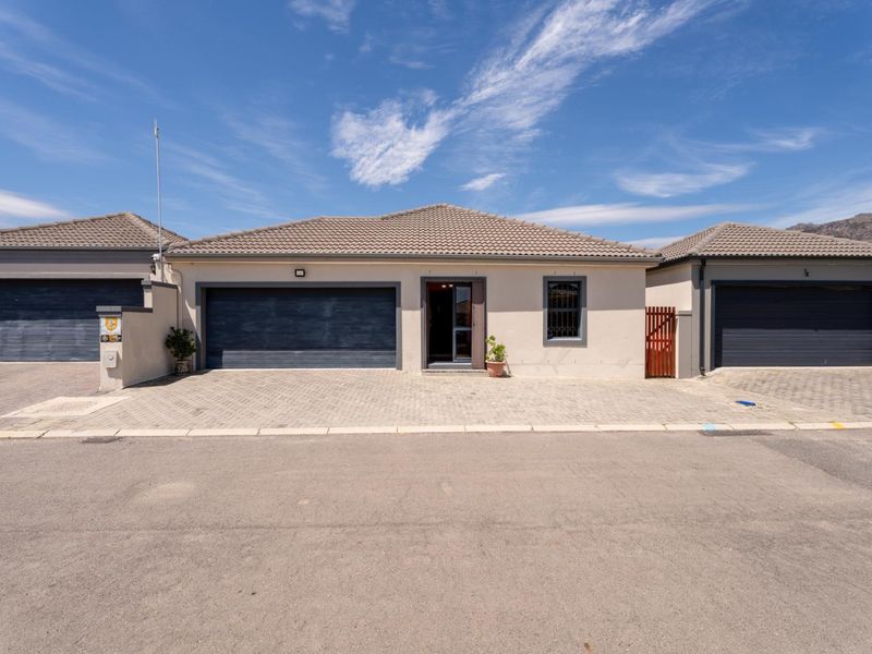 Front elevation of a modern single-story house featuring a tiled roof, paved driveway, and an integrated double garage.