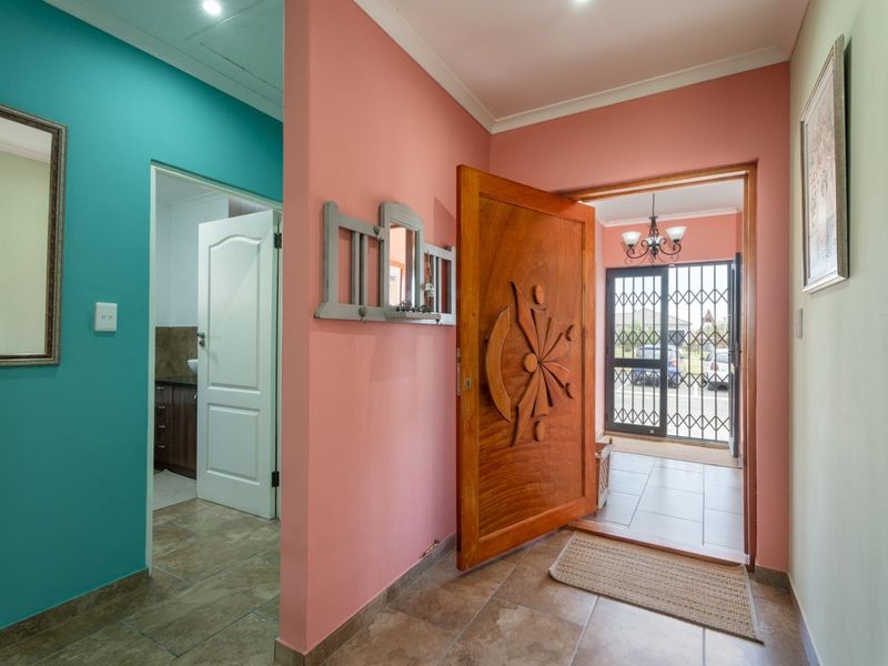 Welcoming entrance hall featuring a decorative solid wood front door, tiled flooring, and a secure metal gate leading to the exterior.