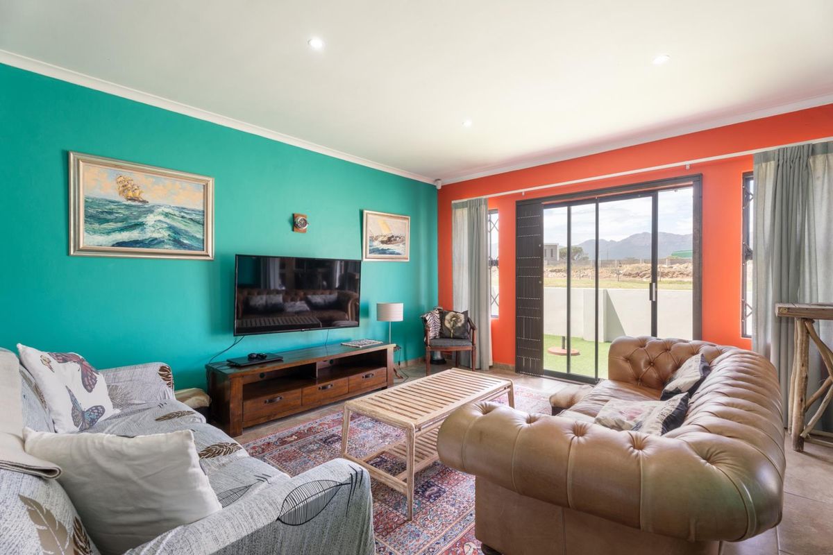 A bright living room featuring bold accent walls, tiled flooring, and a large sliding glass door providing access to an outdoor patio area.