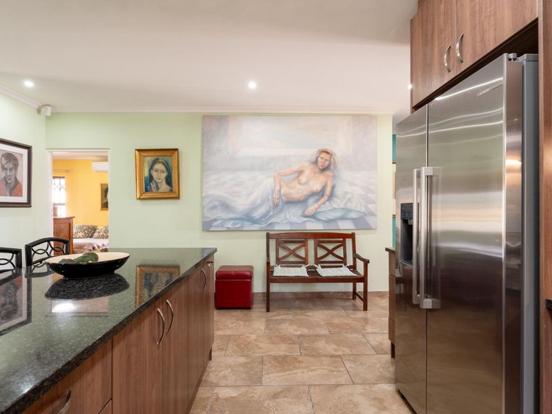 A well-maintained kitchen featuring granite countertops, modern laminate cabinetry, and tiled flooring, providing a functional and clean culinary space.