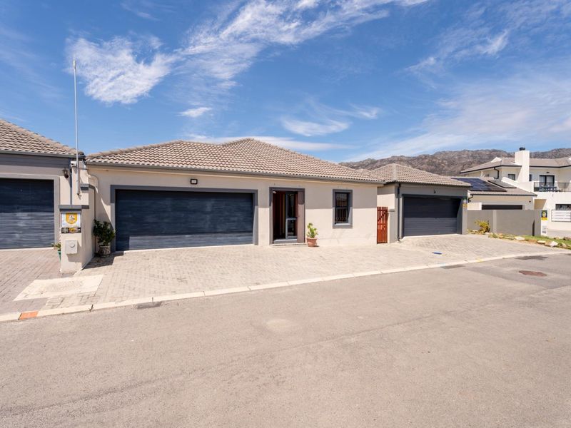 Front exterior view of a modern residential property featuring a double garage, a single garage, and a paved driveway under a clear blue sky.