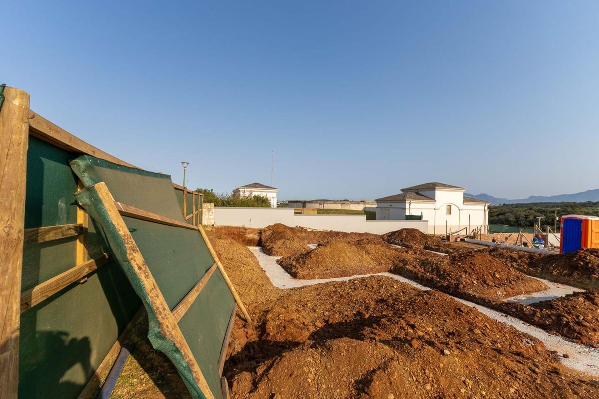 A construction site showing excavated ground and foundation work in progress for a new residential development.