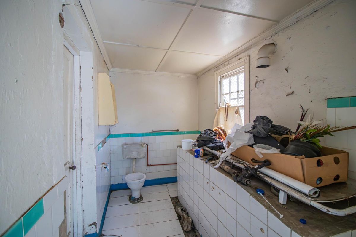 A dilapidated bathroom featuring tiled walls and flooring, requiring significant renovation and repair to restore functionality and aesthetic appeal.