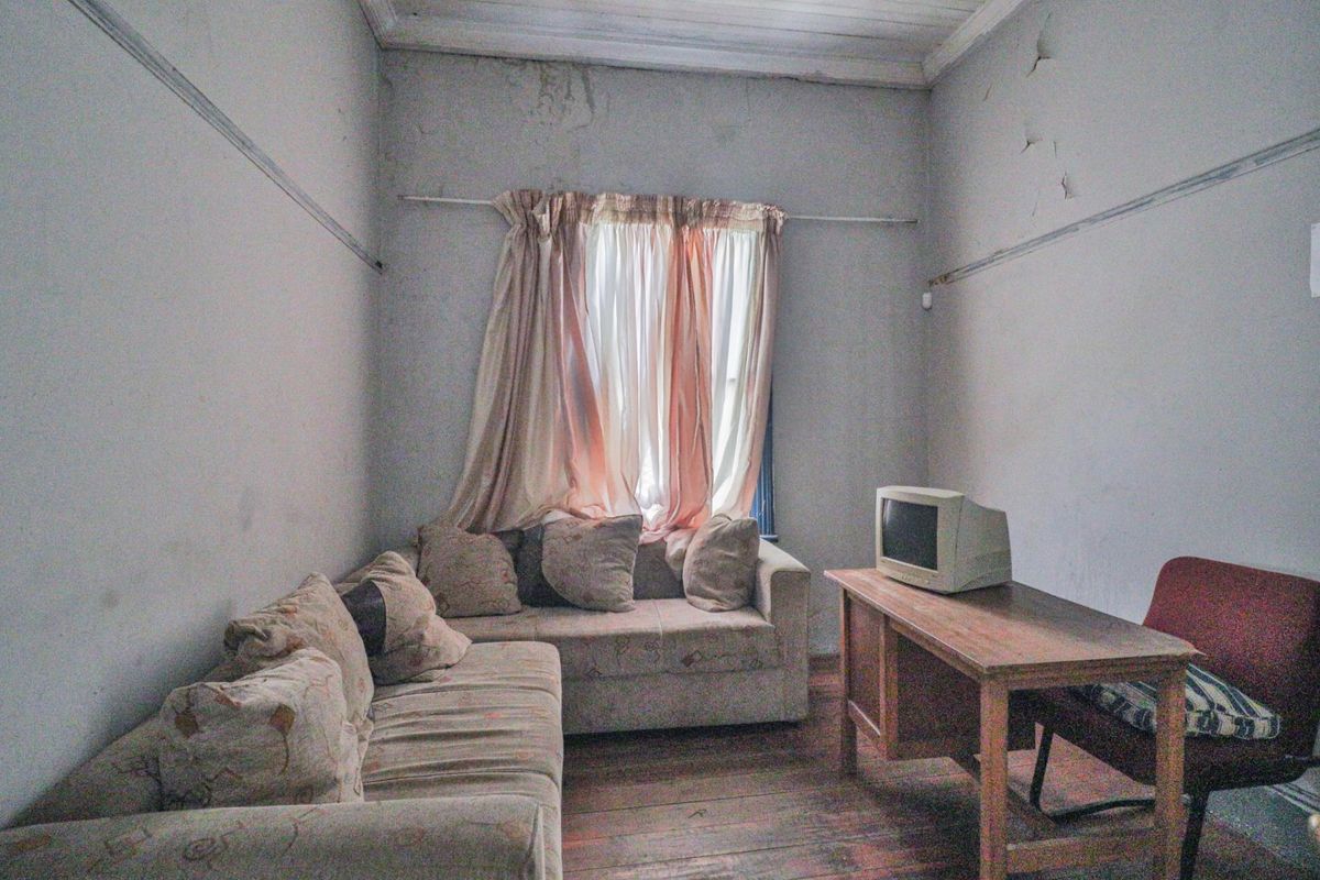 A small, dated room featuring timber flooring and visible wall damage, requiring significant renovation and cosmetic updates to restore its condition.