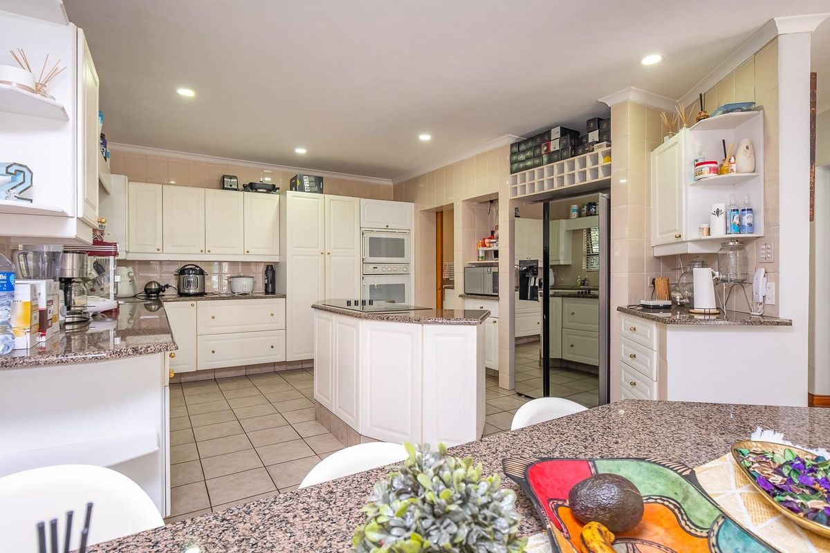 Spacious kitchen featuring granite countertops, built-in oven, integrated cabinetry, and a central island, offering ample storage and workspace for culinary activities.