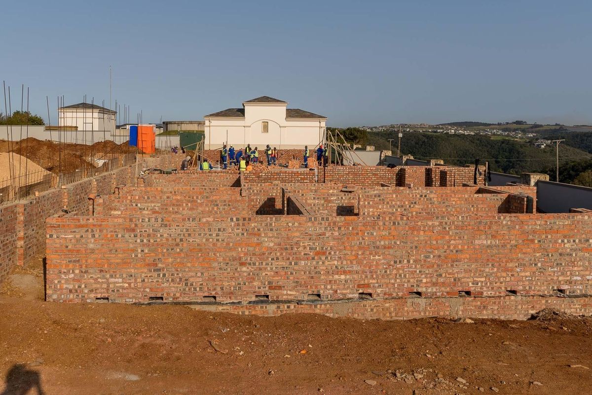 An aerial view of a residential property currently under construction, showing the brickwork foundation and walls in the early stages of development.
