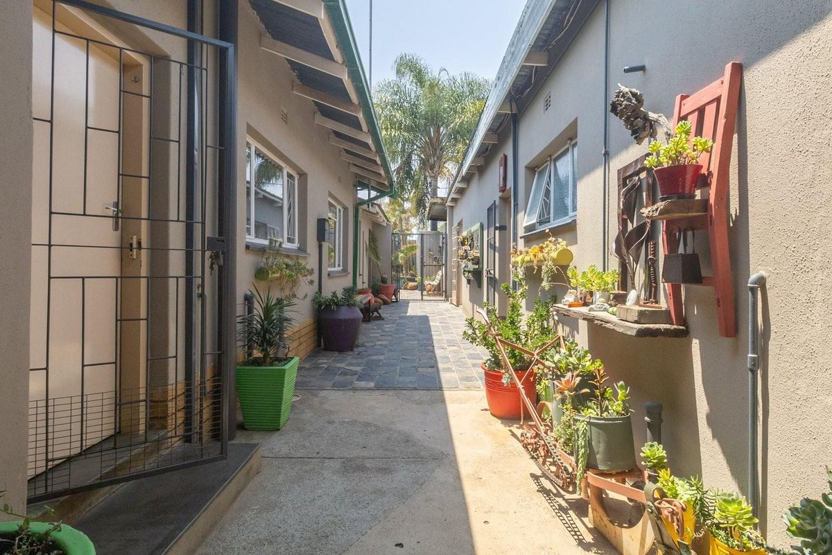 A narrow exterior side passage featuring paved flooring, security gates, and access to the rear garden area.